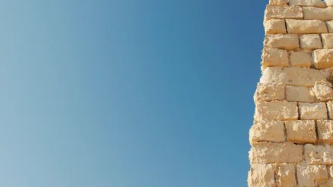 A fragment of a yellow stone wall on a blue sky background Stock Footage