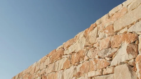 A fragment of a yellow stone wall on a blue sky background Stock Footage
