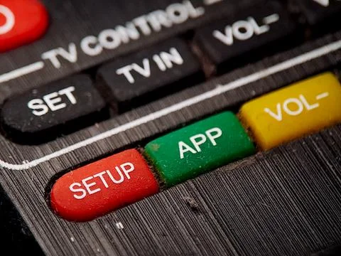 Fragmented television remote featuring vibrant red, green, and yellow butto.. Stock Photos
