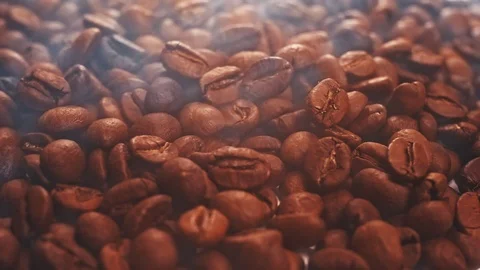 Fragrant coffee beans are roasted in a frying pan, smoke comes from coffee beans Stock Footage 121780492