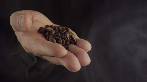 Fragrant freshly roasted coffee beans on a man's palm on a dark background with Vídeo Stock 166332765