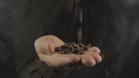 Fragrant freshly roasted coffee beans are sprinkled on the palm of a man on a Stock Footage 166507729