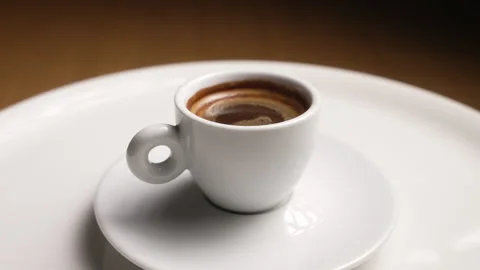 Fragrant hot espresso in a white ceramic cup rotating on a plate Stock Footage 333564570