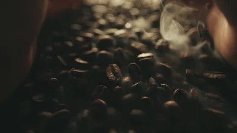 Fragrant roasted coffee beans splashing from man hands. Aromatic smoke and brown Stock Footage 106948858