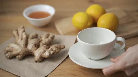 Fragrant tea is poured into a white cup. Ginger, lemon, honey and herbal tea on Stock Footage 156811873