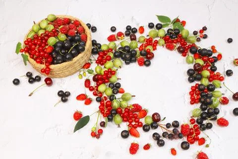 Frame of assorted berries in shape of heart on white background. Copy space. Stock Photos