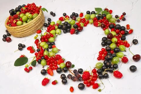 Frame of assorted berries in shape of heart on white background. Copy space. Stock Photos