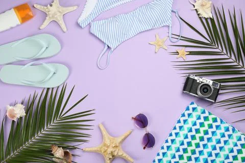 Frame of beach objects on violet background, flat lay. Space for text Stock Photos