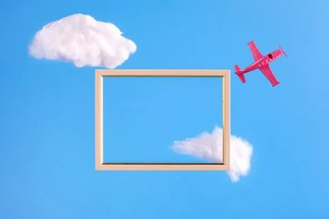 Frame on blue background with abstract clouds and pink airplane Stock Photos