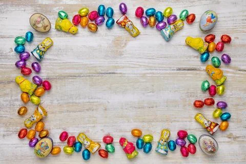 Frame of colourful Easter sweets on wood chocolate eggs chocolate bunnies and Foto stock