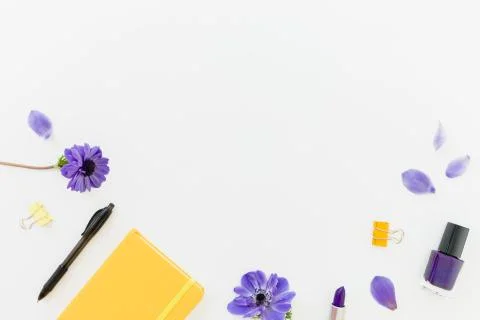 Frame composition with yellow notebook, blue anemones and nail polish on whit Stock Photos