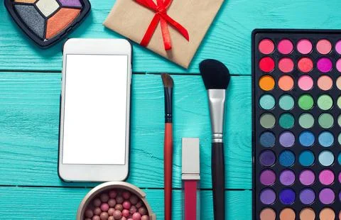 Frame of cosmetics and blank mobile screen on blue wooden background. Top v.. Stock Photos