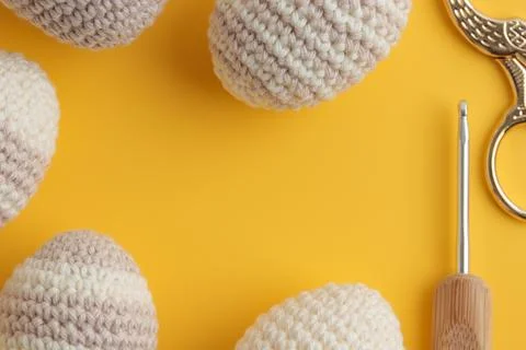 Frame of cute striped pattern crocheted eggs, pastel color on a yellow Foto stock