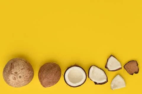 Frame of different coconuts on yellow background. Whole and broken coconuts. Stock Photos