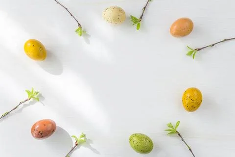 Frame of easter eggs and twig with young leaves on white background; Happy .. Stock Photos