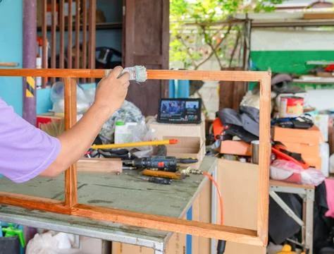 The frame is elevated on a workbench, which is cluttered with various tools.. Stock Photos