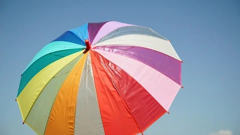 Frame-by-frame video shooting: Multicolored umbrella is spinning. Sky background Stockbeeldmateriaal 103267271
