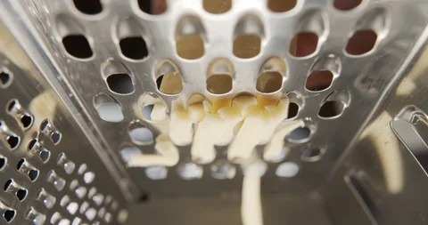 Frame inside metal grater. Close-up grated cheese on metal grater in slow motion Stock Footage 120277870