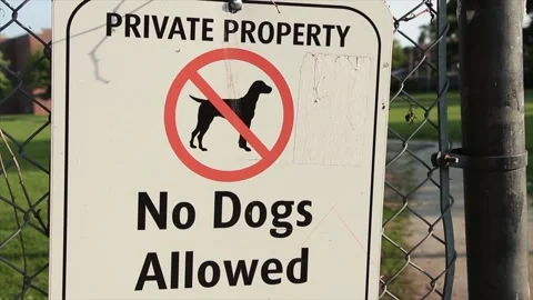 Frame left private property no dogs allowed sign in black writing on white Stock Footage 246137342