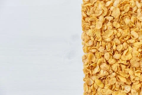 A frame lined with corn flakes. Cornflakes scattered on a wooden table. Stock Photos