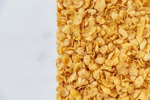 A frame lined with corn flakes. Cornflakes scattered on a wooden table. Stock Photos