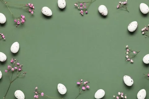 Frame made of Easter eggs and gypsophila flowers on green background Stock Photos