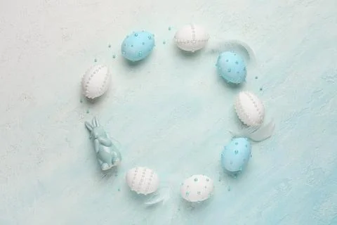 Frame made of Easter eggs decorated with pearls and feathers on blue grunge b Stock Photos
