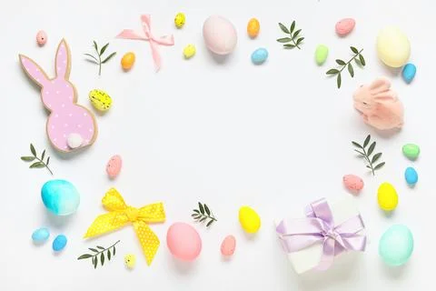 Frame made of Easter eggs, decorative bunnies and green twigs on white backgr Stock Photos