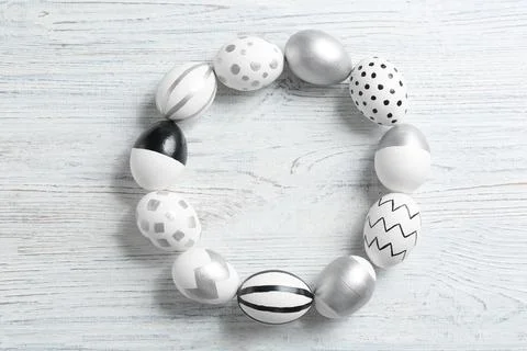 Frame made of painted Easter eggs on wooden background, top view. Space for t Stock Photos