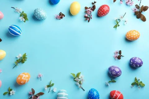 Frame made of painted Easter eggs and blossoming branches on color background Stock Photos