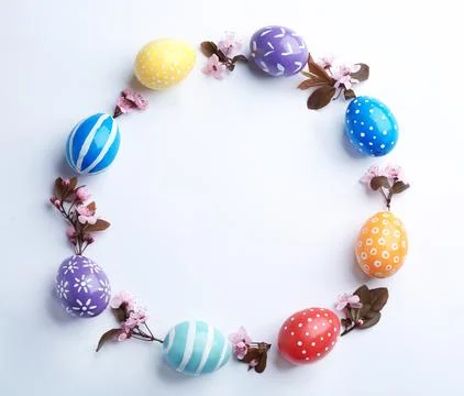 Frame made of painted Easter eggs and blossoming branches on white background Foto stock