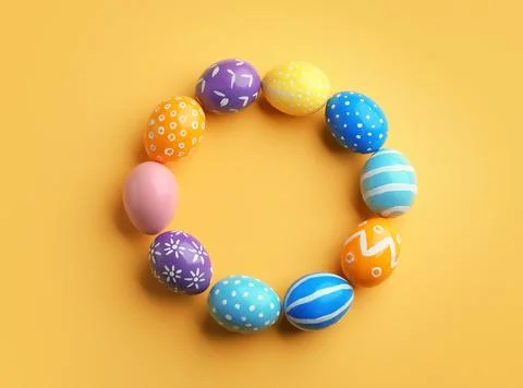Frame made of painted Easter eggs on color background, top view. Space for te Stock Photos