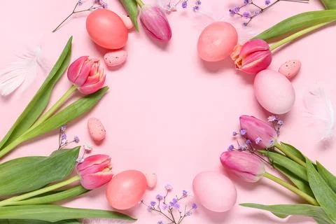 Frame made of painted Easter eggs with beautiful flowers and feathers on pink Stock Photos