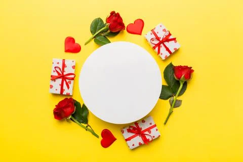 Frame made of rose, git box, heart and blank greeting card mockup on Colored  Foto stock