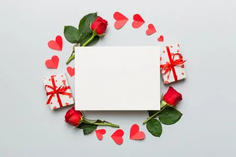 Frame made of rose, git box, heart and blank greeting card mockup on Colored  Fotos de archivo