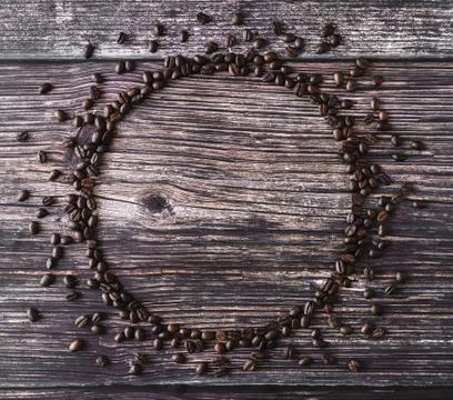 Frame made of spilled coffee beans on a wooden table. Rustic stile. Stock Photos