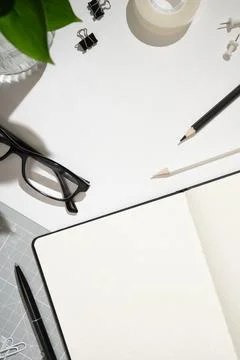 Frame of open dotted notebook, black pen, glasses, paper clips, tape, pencils Stock Photos