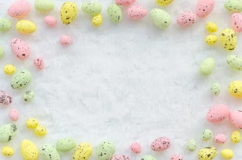 Frame of painted pastel Easter quail eggs on a white background. Top view with Stock Photos