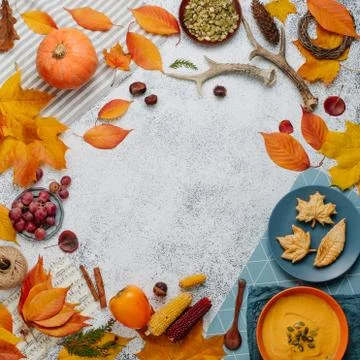 Frame of pumpkin soup, leaf shape cookies and autumn decorations on white sto Stock Photos