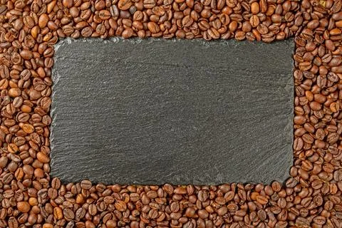 Frame of roasted coffee beans and black stone tiles inside. Place for text Stock Photos