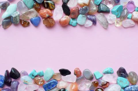 Frame in the shape of a wave of semi-precious minerals on a pink background. Stock Photos