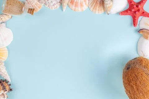 Frame of shells, bottle with sand and coconut on a blue background Stock Photos