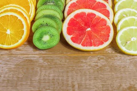 Frame with slice of oranges, lemons, kiwi, grapefruit pattern on wooden bac.. Stock Photos