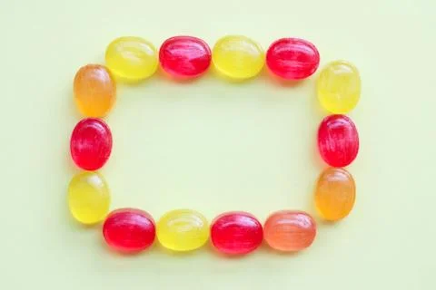 A frame of sweet multi-colored candy lollipops on a light yellow background 写真素材