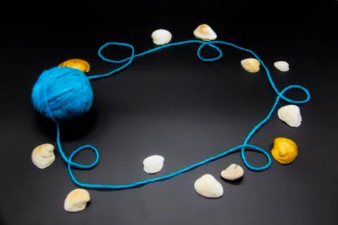 Frame with threads and shells on a black background.  A blue skein of thread. Stock Photos