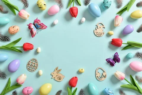 A frame with tulip flowers, Easter colored eggs and butterflies. Stock Photos