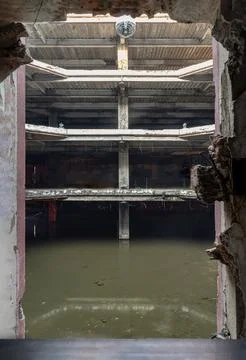 Framed by a crumbling wall aperture, a desolate, multi-tiered concrete buil.. 写真素材