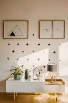 Framed posters on a white wall with plus sign pattern and a scandinavian side Stock Photos
