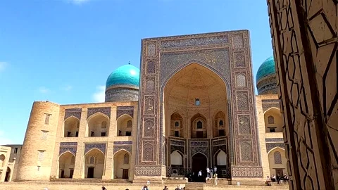 Framed view of Mir-i Arab Madrassah facade with tourists in Bukhara Stock Footage 335571475