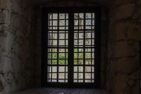 Framed view of a stone wall through a dark iron grille window, with hints of Fotos de archivo